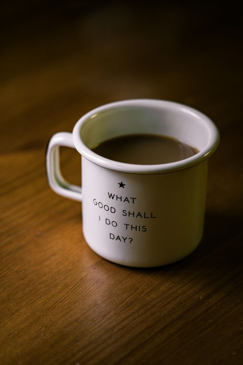A cup of black coffee on a wooden table beside scattered roasted beans