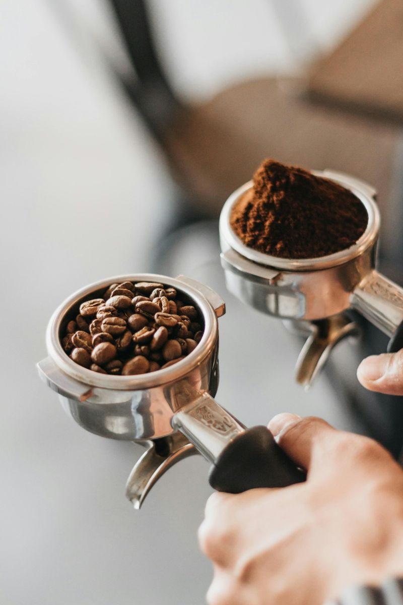 Two espresso portafilters resting beside coffee beans