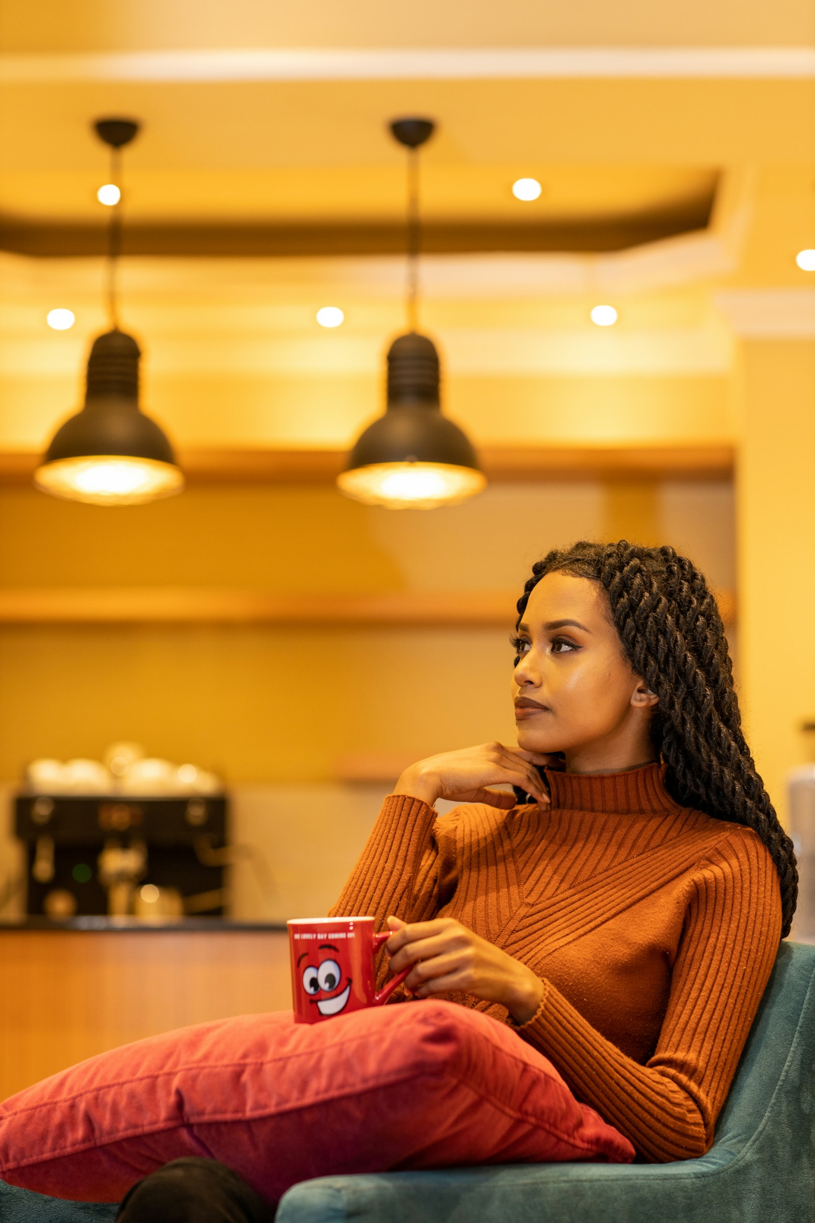 A woman holding a red and white ceramic mug of coffee indoors in Addis Ababa