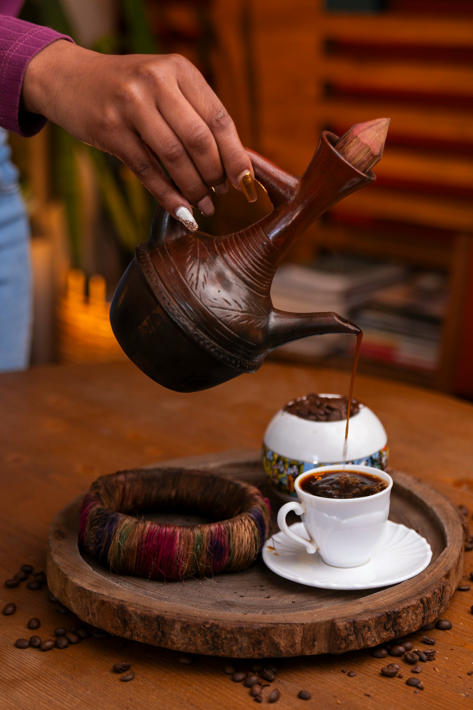 Coffee being poured from a traditional Ethiopian clay jebena into a small white cup