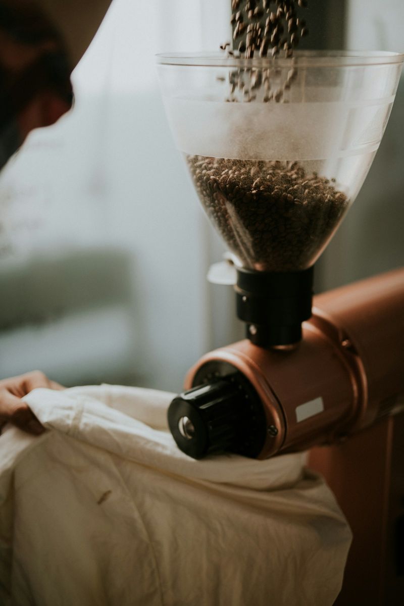 Coffee beans falling from a grinder hopper into the burrs
