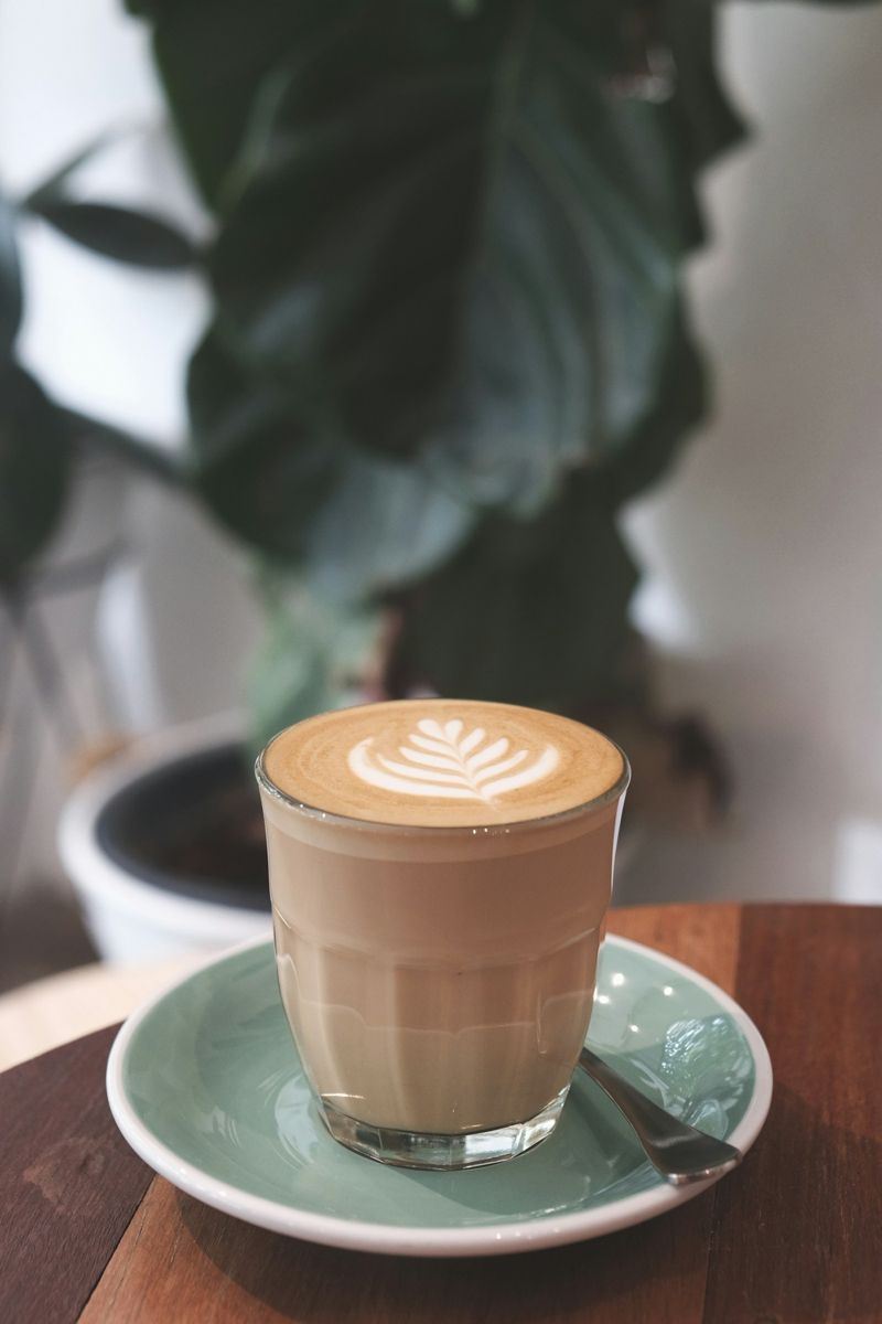 A latte in a tall glass showing a deep band of steamed milk under a thin layer of foam