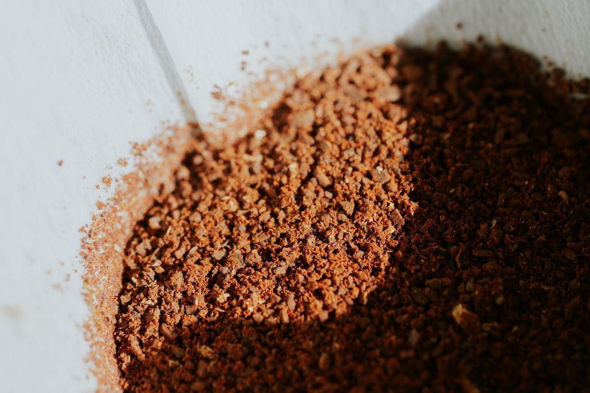 Close-up of medium-ground coffee spilling from a scoop, showing distinct salt-sized grains