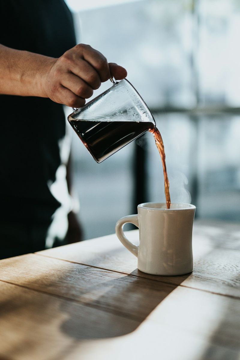 Black coffee being poured into a white mug